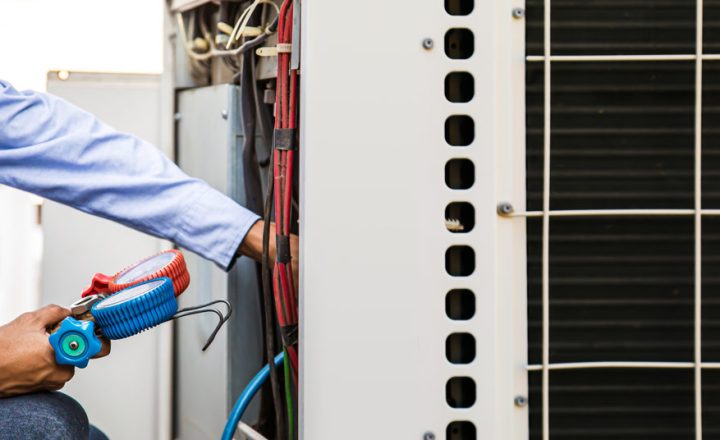 A skilled technician with specialized measuring equipment for filling the air conditioner unit for maintenance purposes and carefully manipulates the gauges and hoses, ensuring proper connections.