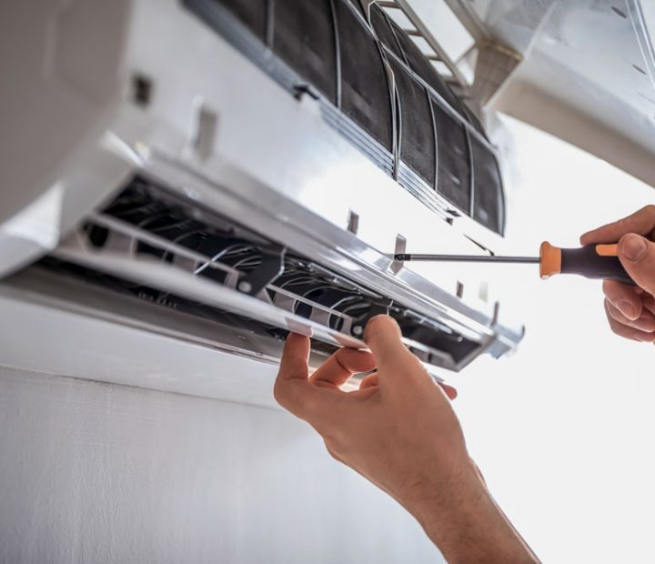 With a screwdriver in hand, an electrician is focused on repairing an air conditioner.