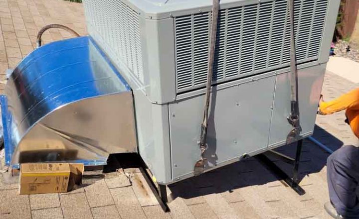 Professional experts carefully working on installing a packaged AC on a residential rooftop