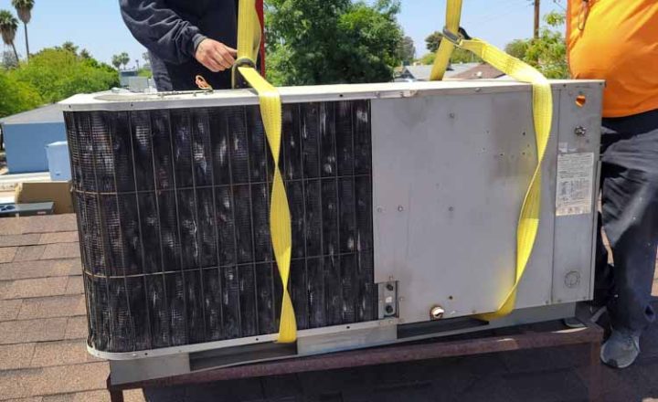 Technicians replacing an old AC unit from a residential rooftop